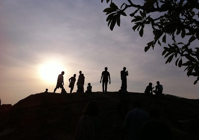 People on a hill backlit by the sun.