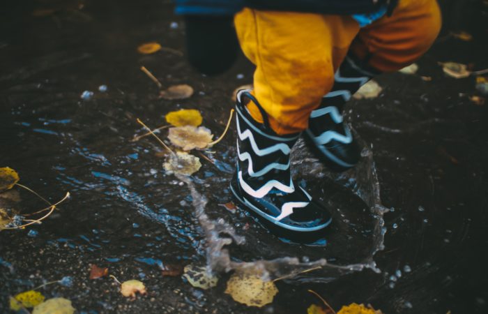 a toddler jumping in a puddle of rain