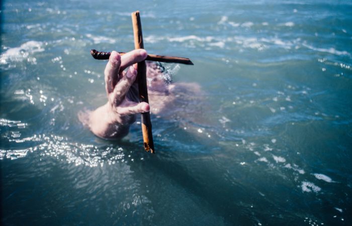 "A person under water holding up a cross"