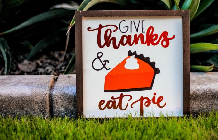 A sign that says "Give thanks and eat pie" with an image of pumpkin pie