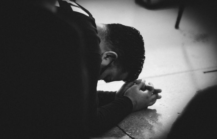 A man kneeling on the floor and praying intently