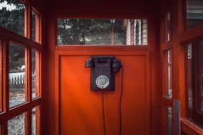 An old-fashioned rotary dial phone in a phone booth