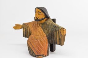 A wooden carving of Jesus with his arms open wide