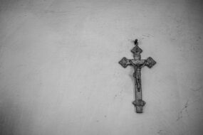 A black and white photo of an old crucifix hanging on a nail
