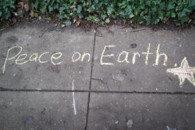 The words "Peace on Earth" written in chalk on a sidewalk