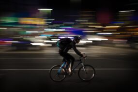 A man biking through downtown Warsaw at night