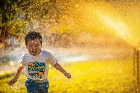 A child running through a sprinkler and laughing