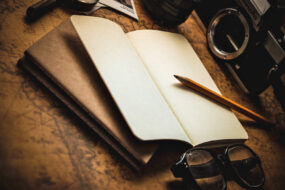 A journal with a pencil and eyeglasses