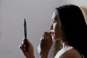 woman looking in mirror taking off makeup